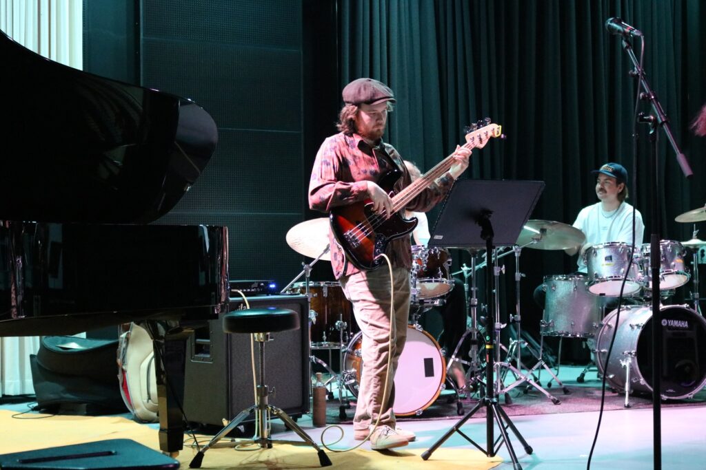 Henkilö soittaa kitaraa, taaempana istuu rumpali.