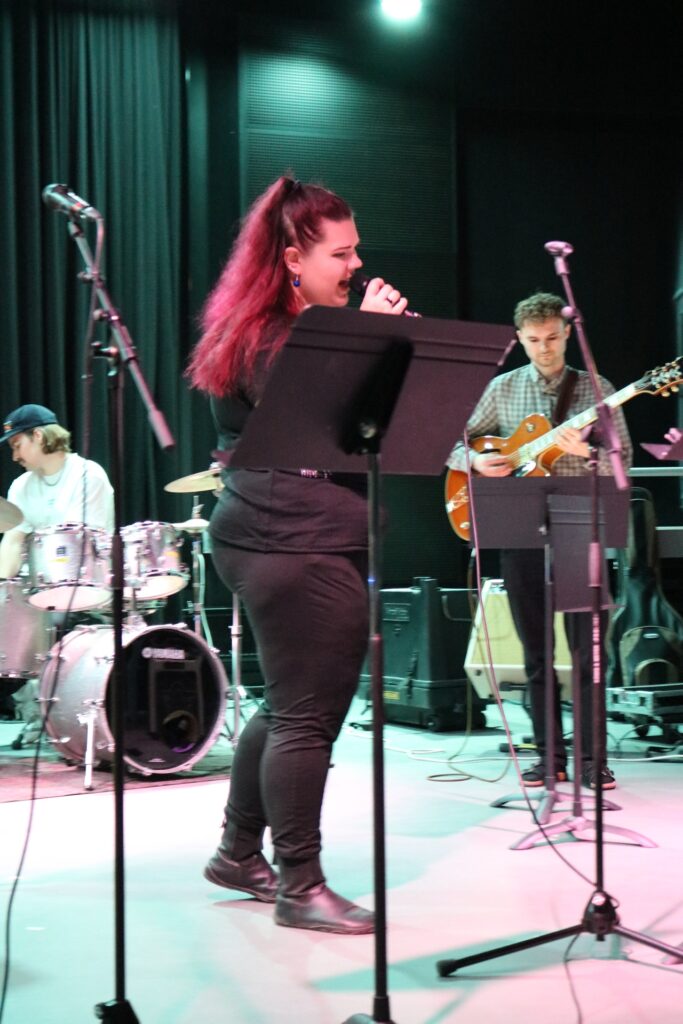 Etualla naislaulaja, taustalla rumpali ja kitaristi.